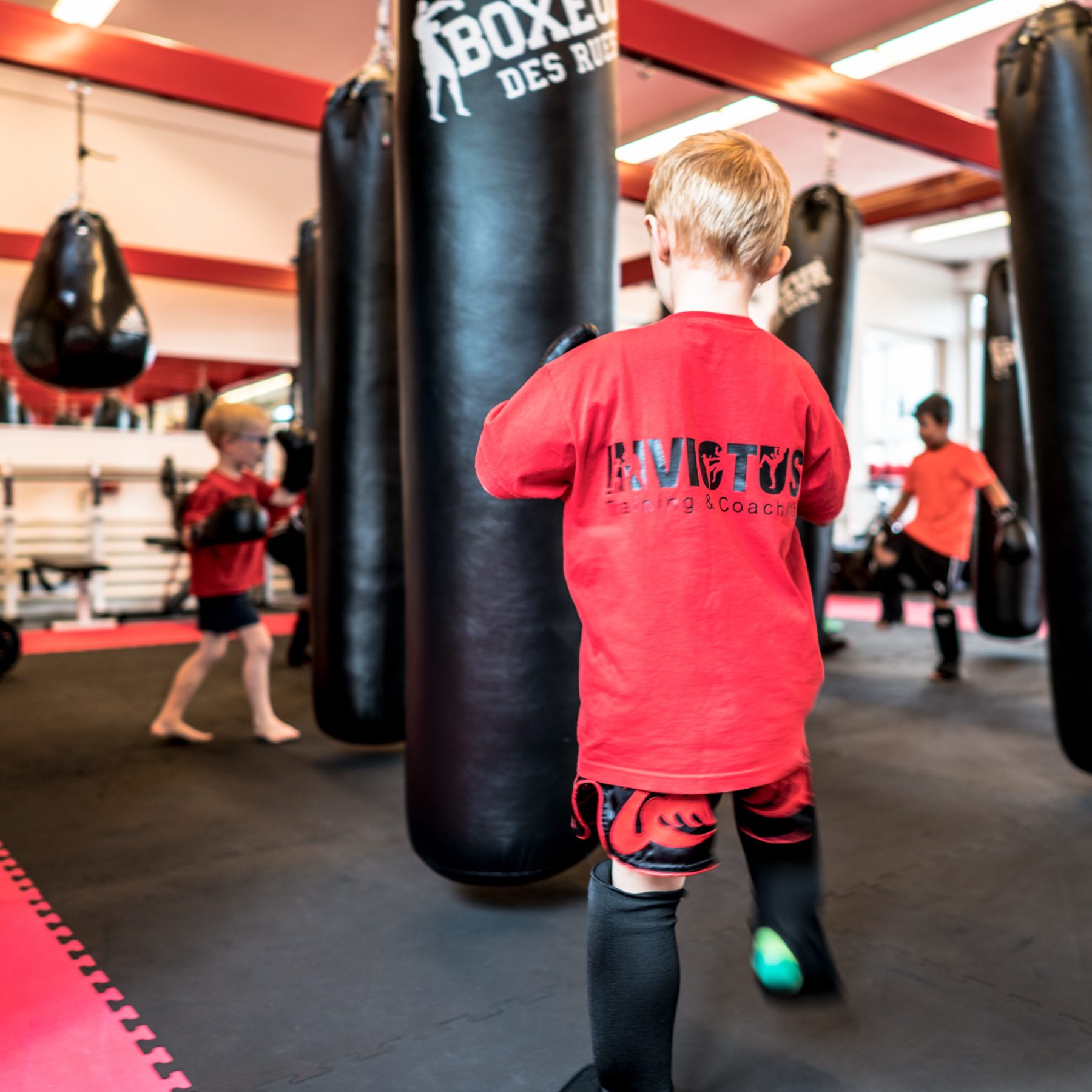 Kind im Invictus-Shirt trainiert am Sandsack